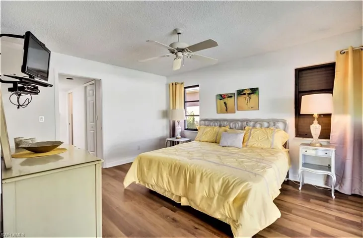 The Master bedroom is quite large with a textured ceiling, wood-type flooring, and ceiling fan