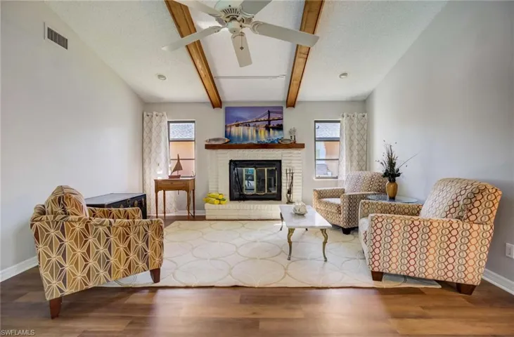 Living room with ceiling fan, plenty of natural light, wood-type flooring, and a brick fireplace