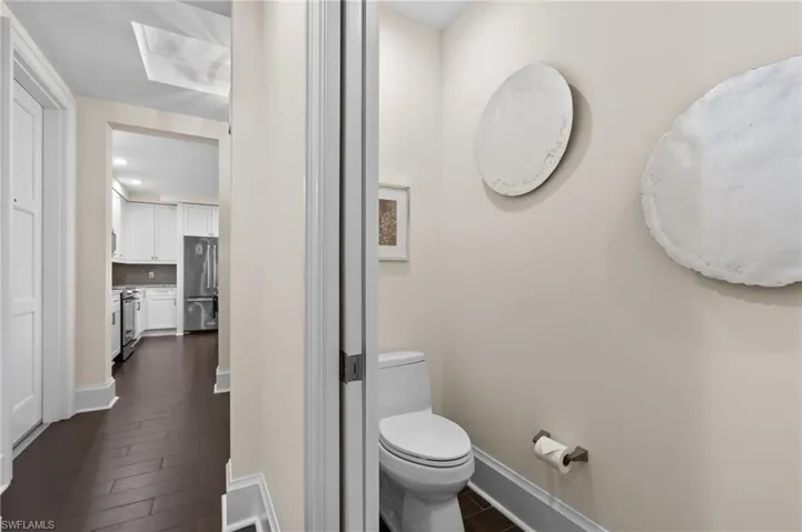 Half bathroom with dark wood finished floors and decorative backsplash