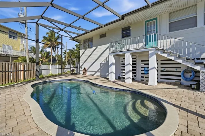 View of pool featuring large screen lanai and ample outdoor seating space - Virtually Edited Image