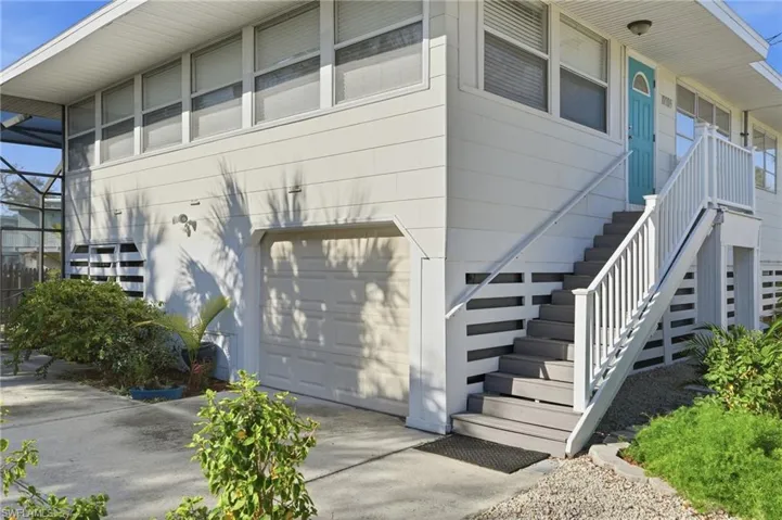 Doorway to property featuring a garage and driveway - Virtually Edited Image