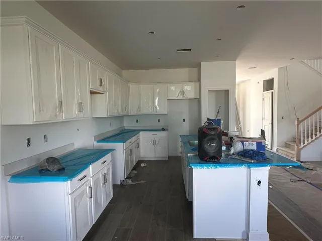Kitchen with white cabinetry, dark hardwood / wood-style flooring, and a kitchen island
