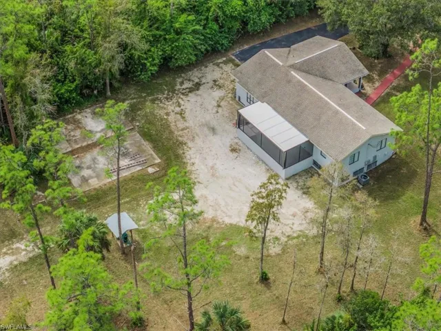 Aerial view of property and surrounding area with a tree filled landscape