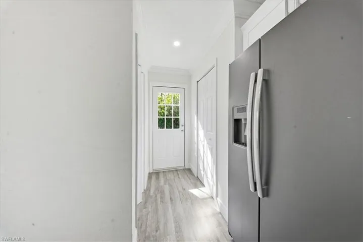 Corridor with crown molding, light wood-type flooring, and recessed lighting