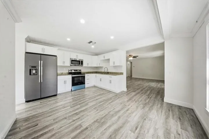 Kitchen featuring appliances with stainless steel finishes, white cabinets, light wood finished floors, recessed lighting, and open floor plan