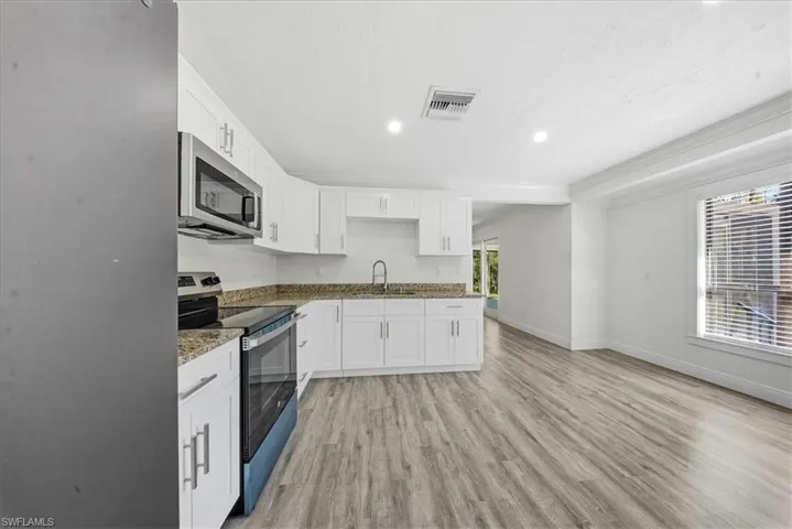 Kitchen with stainless steel appliances, light wood-style flooring, recessed lighting, white cabinetry, and healthy amount of natural light