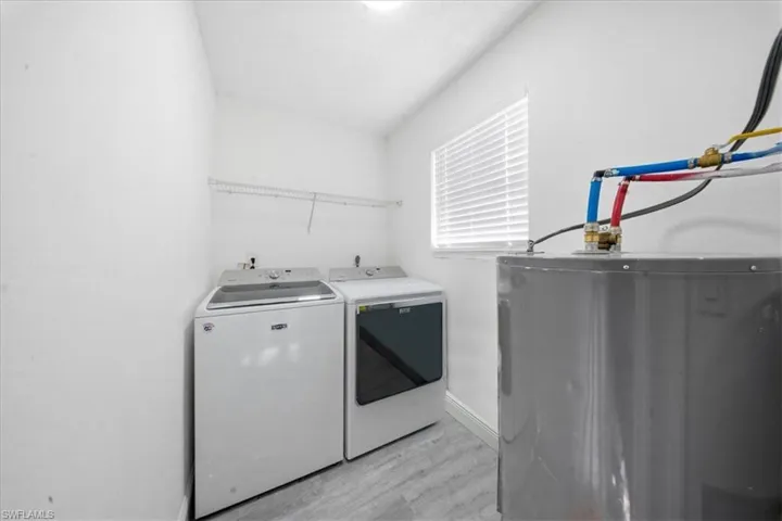 Laundry area featuring water heater, light wood-style flooring, and washer and dryer