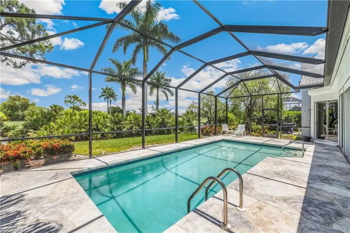 View of swimming pool with screened enclosure and a patio area