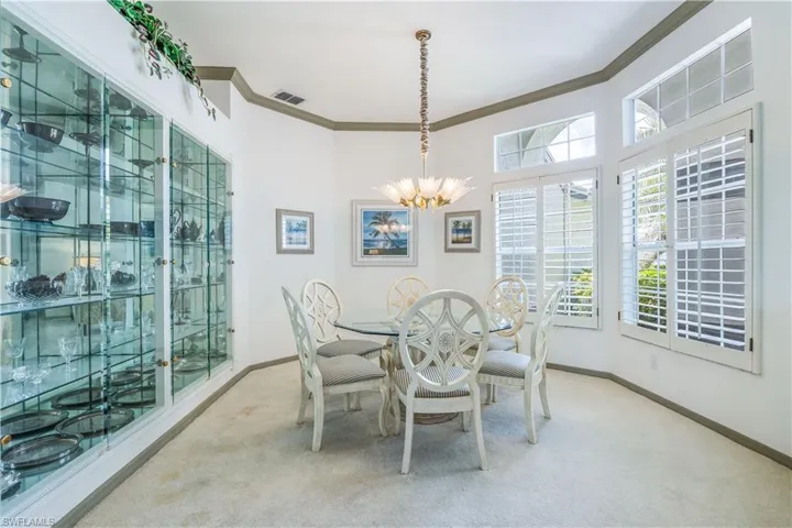 Carpeted dining space with a chandelier glass enclosed cabinets