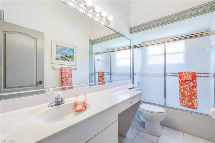 Full Guest bathroom with vanity, tile flooring, bath / shower combo with sliding glass door