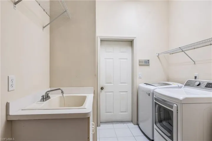 light tile flooring, washer, dryer, small closet and utility sink