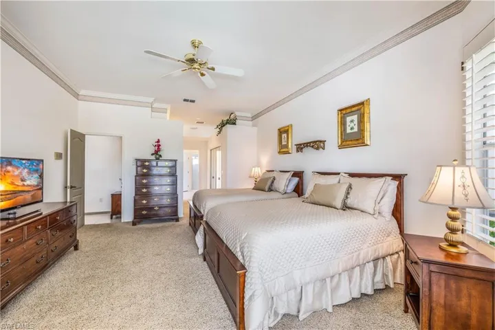 Carpeted Primary  bedroom crown molding, multiple windows, slider to pool and ceiling fan