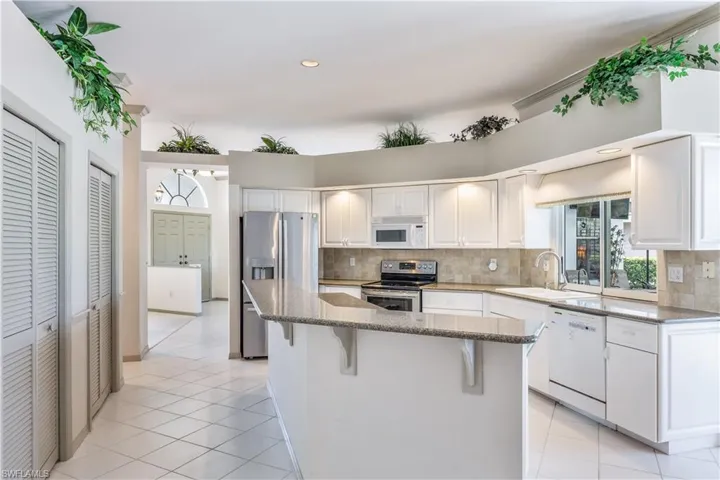 Kitchen white cabinets, granite, pantry, decorative backsplash, and light tile flooring
