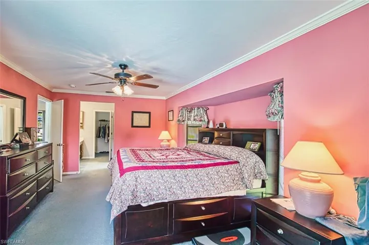 Carpeted bedroom featuring crown molding and a ceiling fan