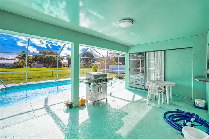 View of pool featuring a sunroom, glass enclosure, a patio, and grilling area