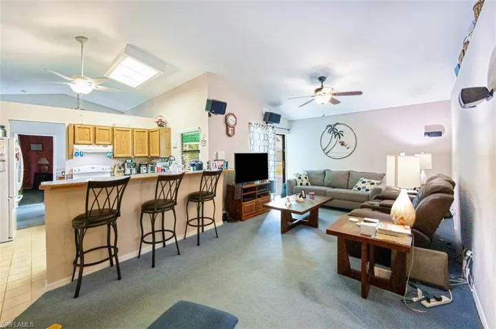 Living room featuring ceiling fan, lofted ceiling, and light colored carpet