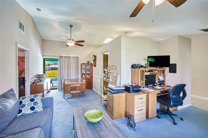 Carpeted office with lofted ceiling and a ceiling fan