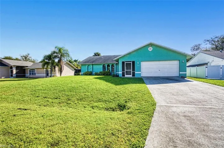 Single story home with concrete driveway, a front yard, stucco siding, and an attached garage