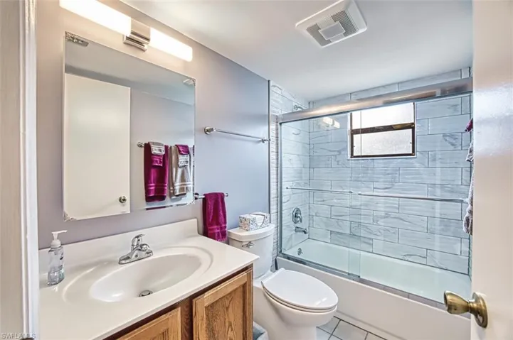 Full bath featuring enclosed tub / shower combo, vanity, and tile patterned flooring