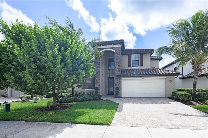 Mediterranean / spanish house with decorative driveway, a tiled roof, stucco siding, and a front lawn