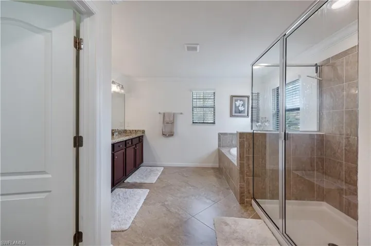 Master Full bathroom featuring a bath, double vanity, tile patterned flooring, a chandelier, and ornamental molding