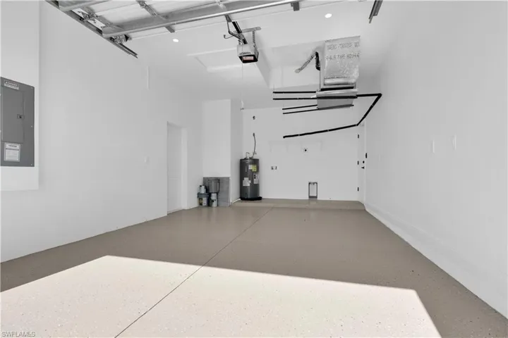 Garage featuring electric panel, water heater, and a garage door opener