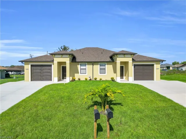Prairie-style home with a front yard, concrete driveway, stucco siding, and a garage