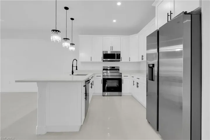Kitchen featuring appliances with stainless steel finishes, white cabinetry, pendant lighting, recessed lighting, and a peninsula