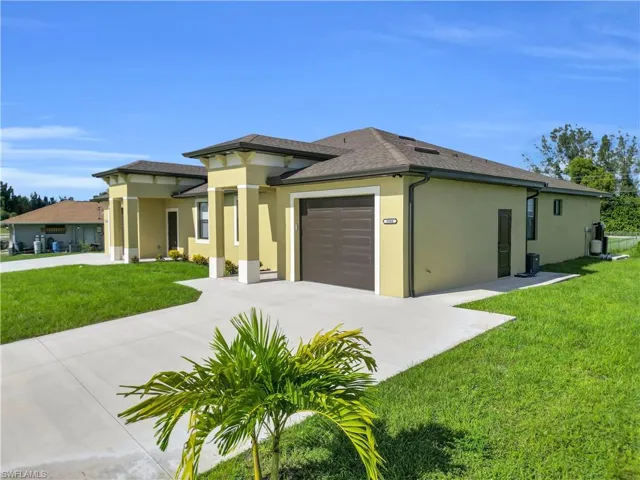 Prairie-style house featuring a front lawn, stucco siding, driveway, and a garage