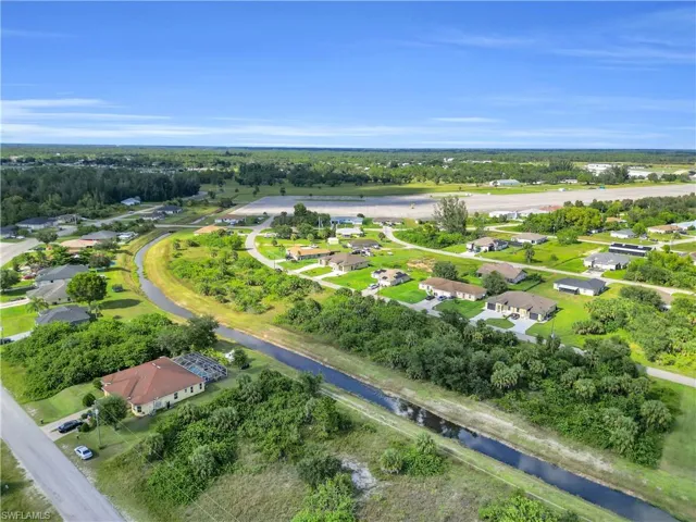 Aerial perspective of suburban area featuring a tree filled landscape and a nearby body of water