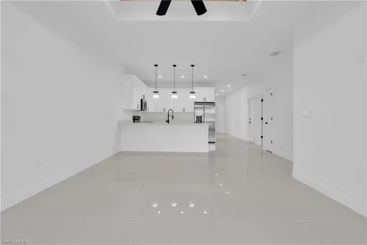 Unfurnished living room featuring light tile patterned flooring, recessed lighting, a ceiling fan, and a raised ceiling