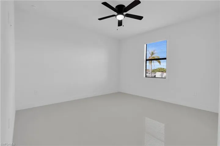 Empty room featuring a ceiling fan and baseboards