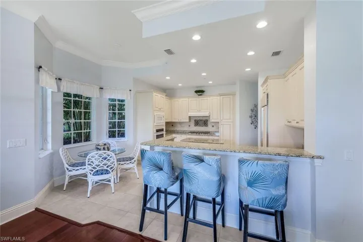 Kitchen featuring kitchen peninsula, light wood-type flooring, a kitchen bar, white microwave, and ornamental molding
