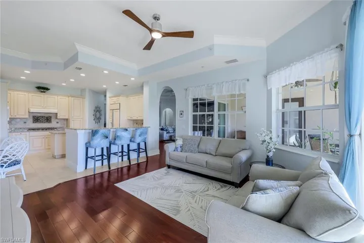 Living room featuring light wood-type flooring, ceiling fan, and crown molding