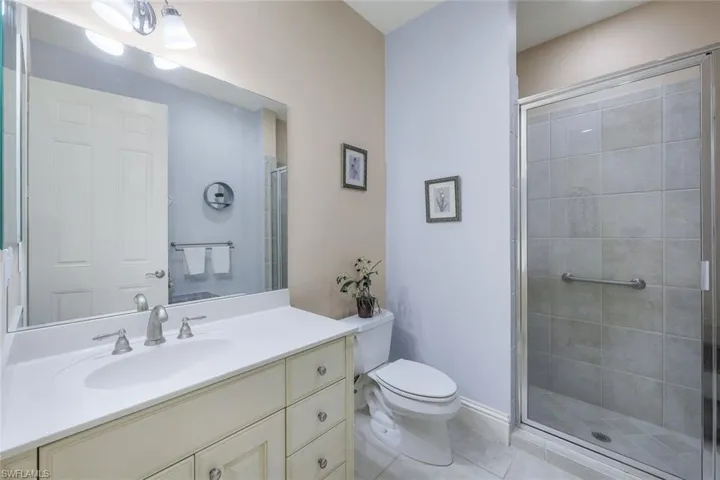 Bathroom featuring toilet, vanity, tile patterned floors, and walk in shower
