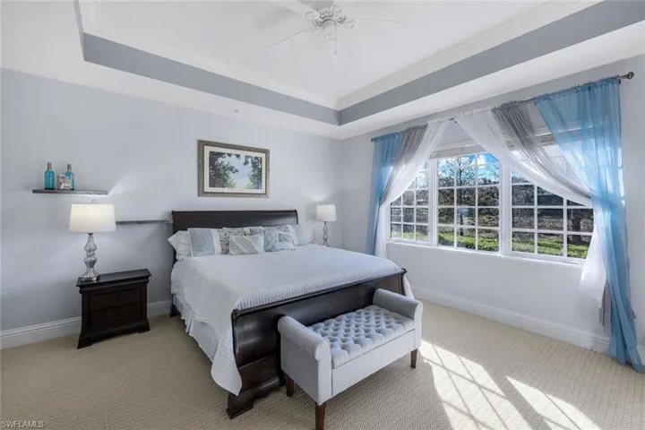 Bedroom featuring a raised ceiling, ceiling fan, crown molding, and light colored carpet