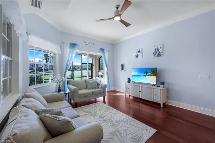 Living room with crown molding, ceiling fan, and dark wood-type flooring