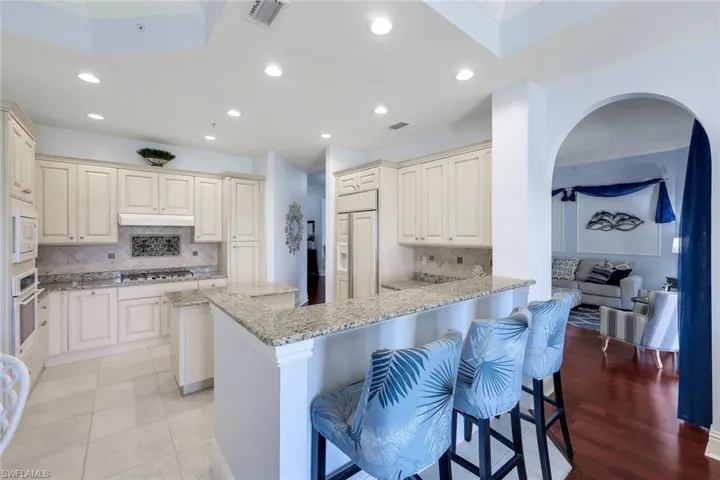 Kitchen with a kitchen breakfast bar, tasteful backsplash, kitchen peninsula, crown molding, and appliances with stainless steel finishes