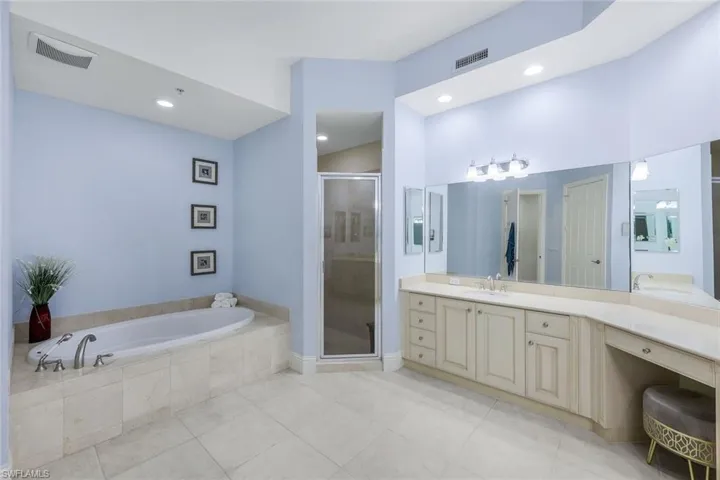 Bathroom featuring tile patterned floors, vanity, and plus walk in shower