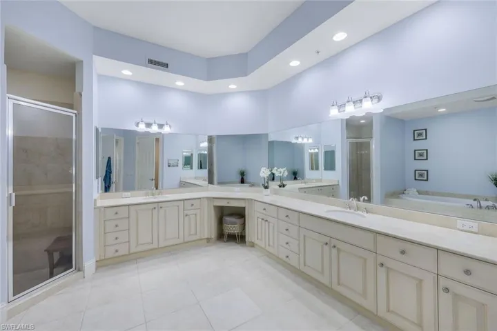 Bathroom featuring vanity, tile patterned flooring, plus walk in shower, and a towering ceiling