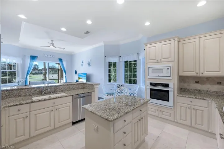 Kitchen with tasteful backsplash, light stone countertops, sink, and appliances with stainless steel finishes