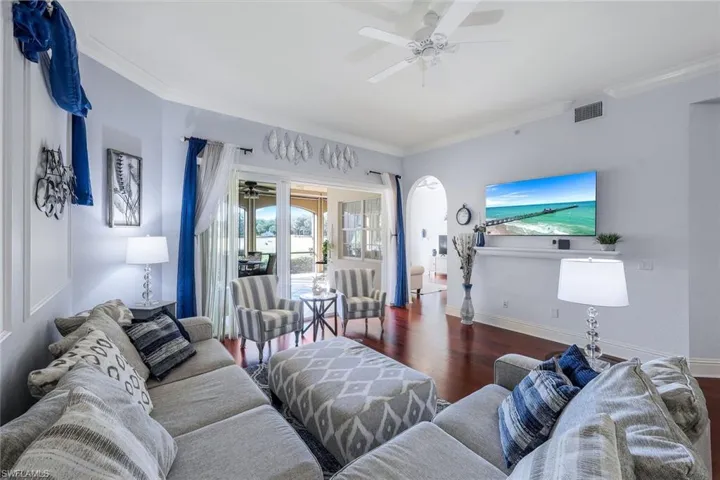 Living room featuring ornamental molding, ceiling fan, and dark wood-type flooring