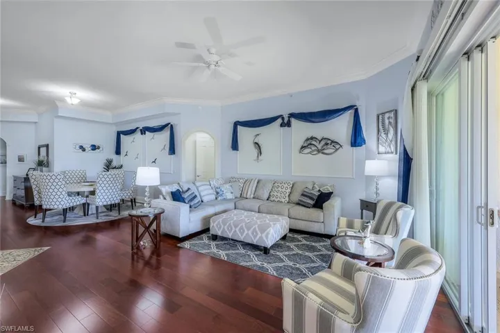 Living room featuring crown molding, ceiling fan, and dark wood-type flooring