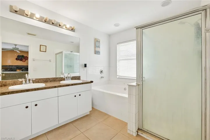 Ensuite bathroom featuring a stall shower, a garden tub, tile patterned floors, double vanity, and a ceiling fan