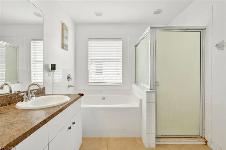 Full bathroom featuring vanity, a garden tub, a stall shower, and tile patterned floors