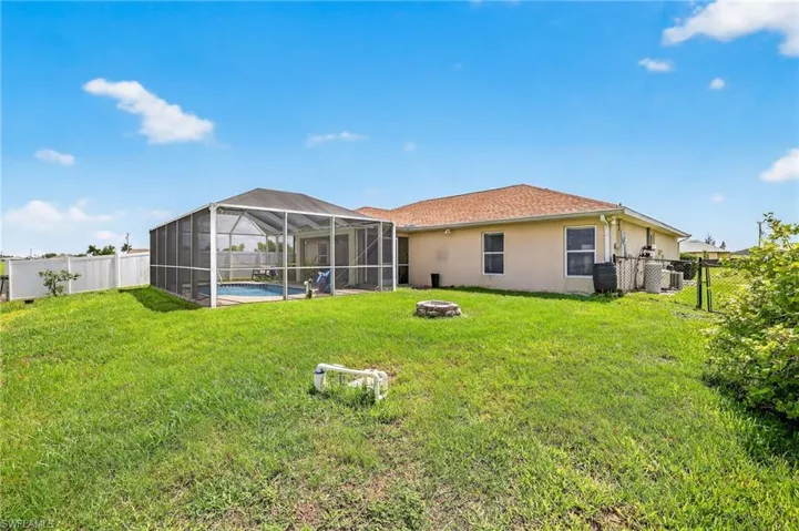 Back of house with an outdoor fire pit, stucco siding, and a fenced backyard