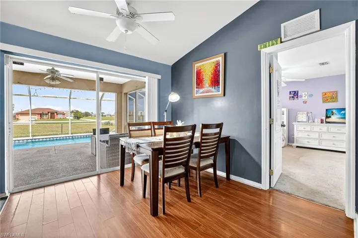 Dining room with a ceiling fan, vaulted ceiling, and wood finished floors