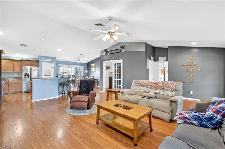 Living area with ceiling fan, lofted ceiling, light wood finished floors, and recessed lighting