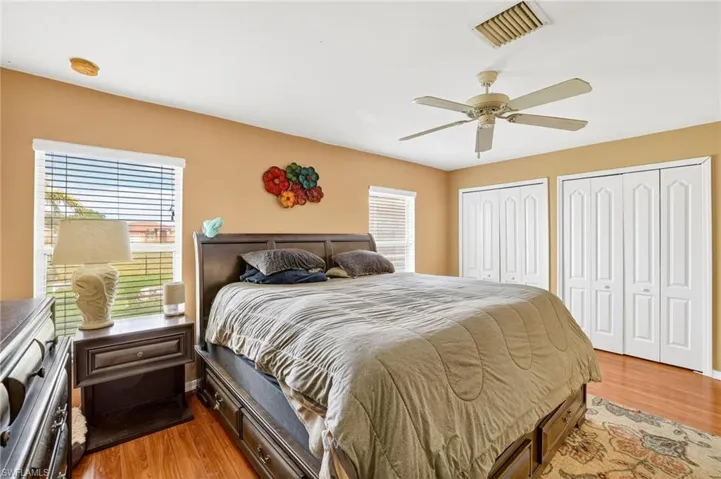Bedroom featuring multiple closets, wood finished floors, and ceiling fan