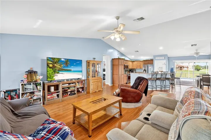 Living room with ceiling fan, lofted ceiling, light wood-type flooring, and recessed lighting